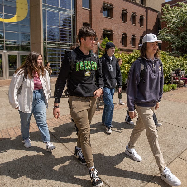 Group of students walking outside with the Lillis Business Complex in the background