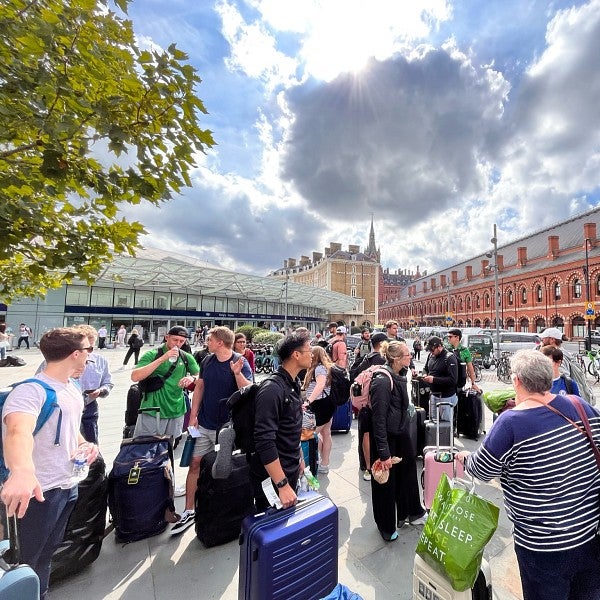 This candid shot depicts a group of MBA students gathered with their luggage on the streets of Paris on a sunny day.