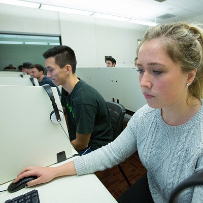 Several students sitting at individual stations working on computers.