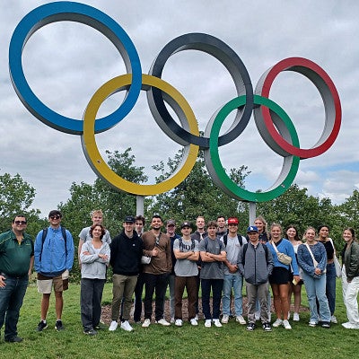 UO instructor Yoav Dubinsky and a group of sports business students stand beneath a statue of the Olympic rings in London