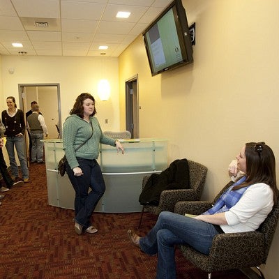 Study participants waiting in the reception area sitting on chairs and lean on desks talking to each other