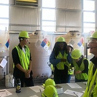 Members of the Net Impact group laugh together while wearing reflective vests and hard hats during a site visit